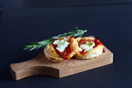 Bruschetta with goat cheese, tomato, and fresh herbs on a wooden board